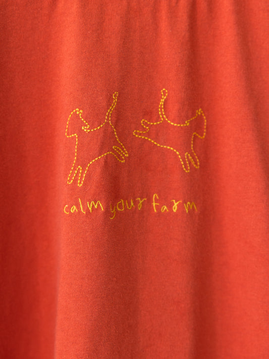 Red fabric with gold embroidered reindeer and 'calm your farm' text